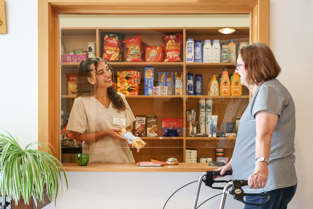 Eine Seniorin kauft am Kiosk der Seniorenresidenz Kleinigkeiten ein.